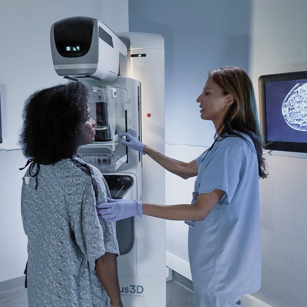 woman radiology technologist speaks to mammogram patient