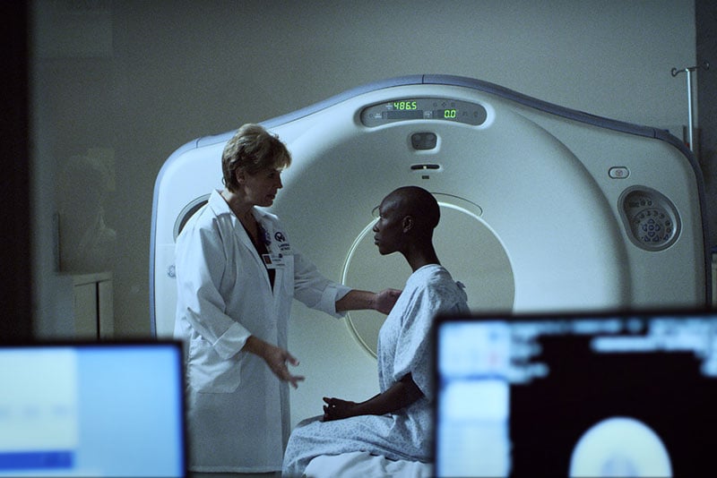 Radiology technologist speaks to patient in gown
