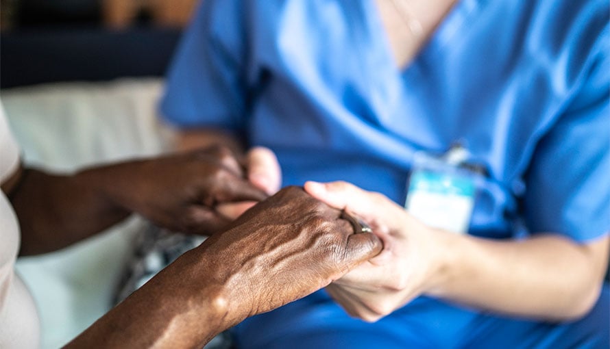 A nurse holding a patient's hands