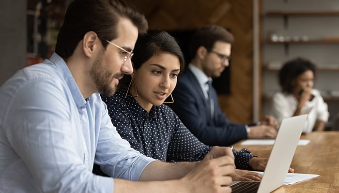 A man and woman working at a laptop computer