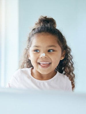 A young girl with sunscreen on her nose depicting sun safety
