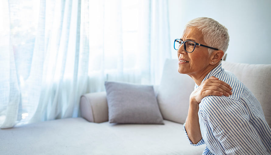 A woman rubs her shoulder near her neck