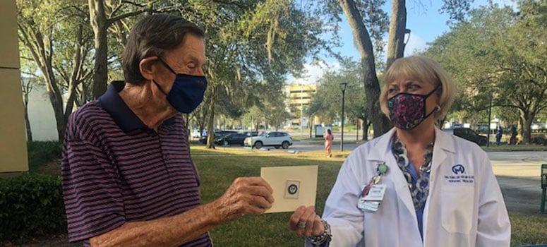 Bruce Mackey gives the PFAC Award of Excellence to Cassondra Vonnes while wearing masks.