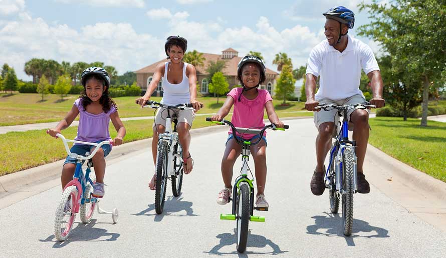 family riding bikes through subdivision