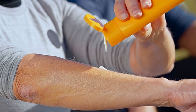 man applying sunscreen at beach