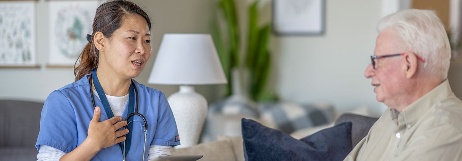 A woman doctor talks to an older man patient on a couch about SLL cancer.