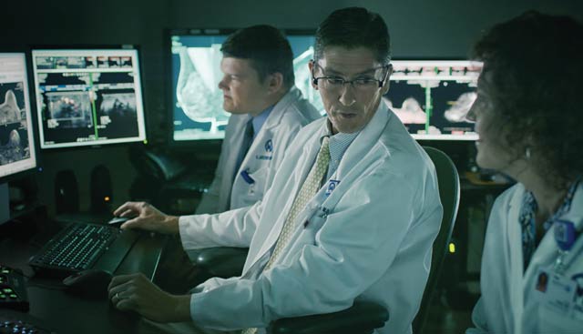 Doctors in darkroom looking at images and discussing the latest breast cancer screening technologies at Moffitt