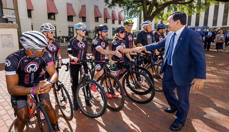 Dr. Patrick Hwu greets bicyclists at Moffitt Day