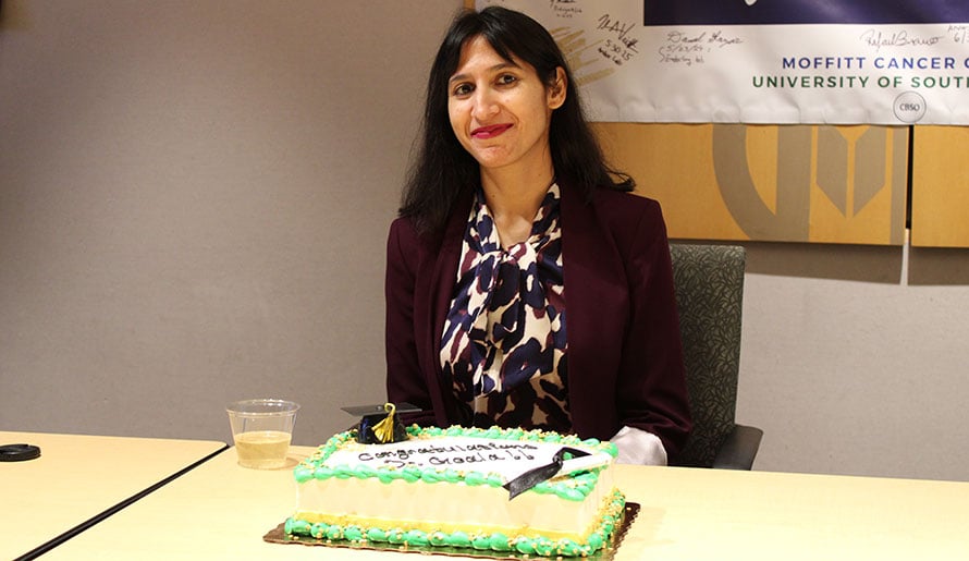 Dr. Goala sitting in front of celebration cake