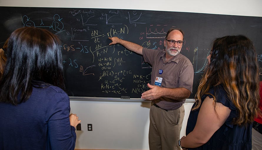 a faculty member working at a chalkboard