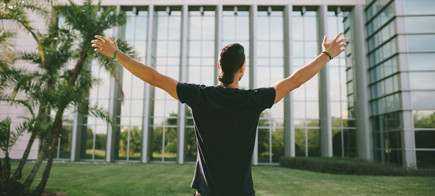 a man stands with open arms in front of Moffitt