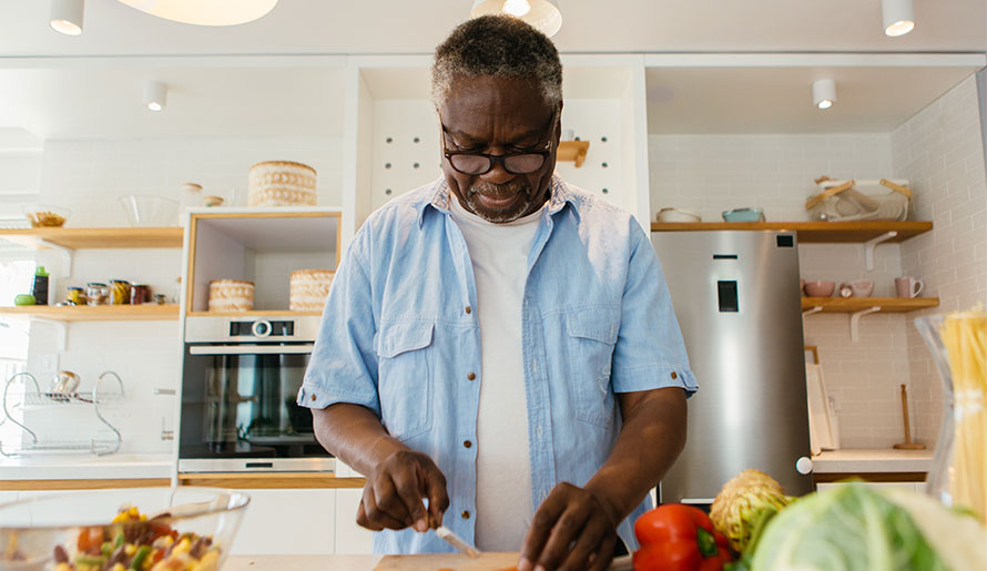 Man in kitchen chopping vegetables