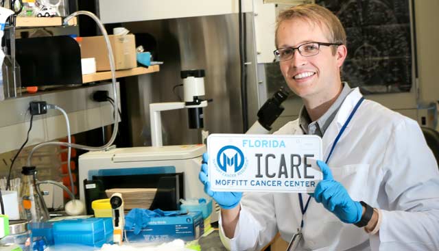 A researcher holds a Moffitt License Plate