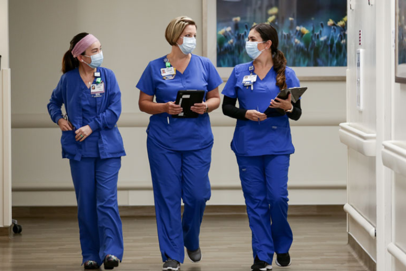 Three oncology nurses in the Tampa Bay area talking in the hospital hallway.