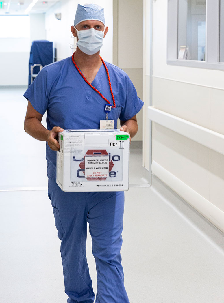 Alexander Dojcinovski, experimental cell therapies supervisor, transports a patient’s tumor and circulating T cells from the operating room at Moffitt McKinley Hospital to the cell therapies lab next door.