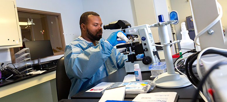 Abraian Miller, experimental cell therapy technologist, examines the cells under a microscope during quality control testing.