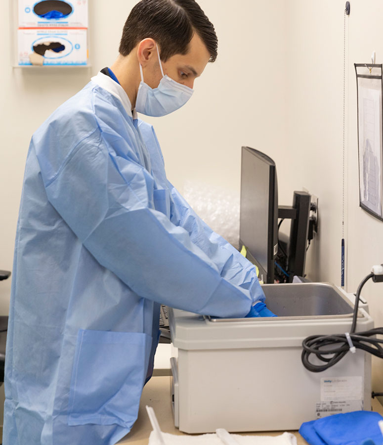 Sannasardo places a bag filled with TIL in a water bath to thaw before being infused into a patient.