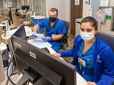 Veronica Mullen, RN, foreground, works with Ivan Ross, RN, to perform a chemo check in the Immune Cell Therapy unit at Moffitt. 