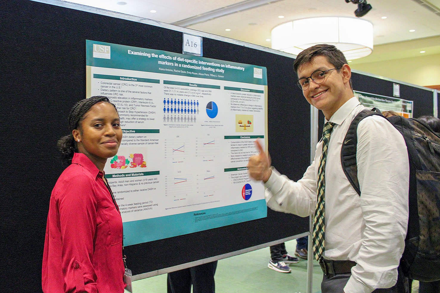 Interns give a thumbs up next to their poster