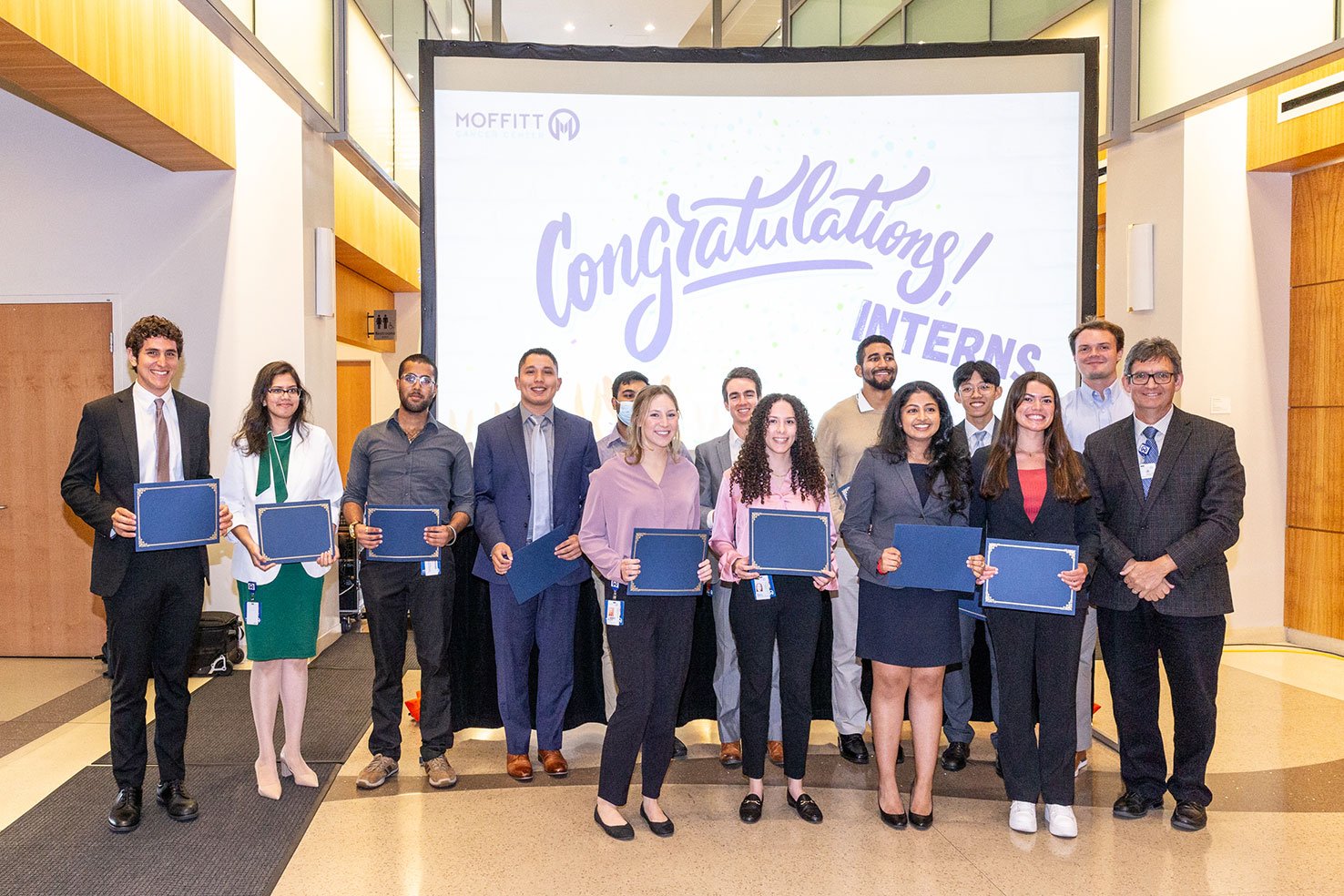 Interns pose in front of a congratulations sign