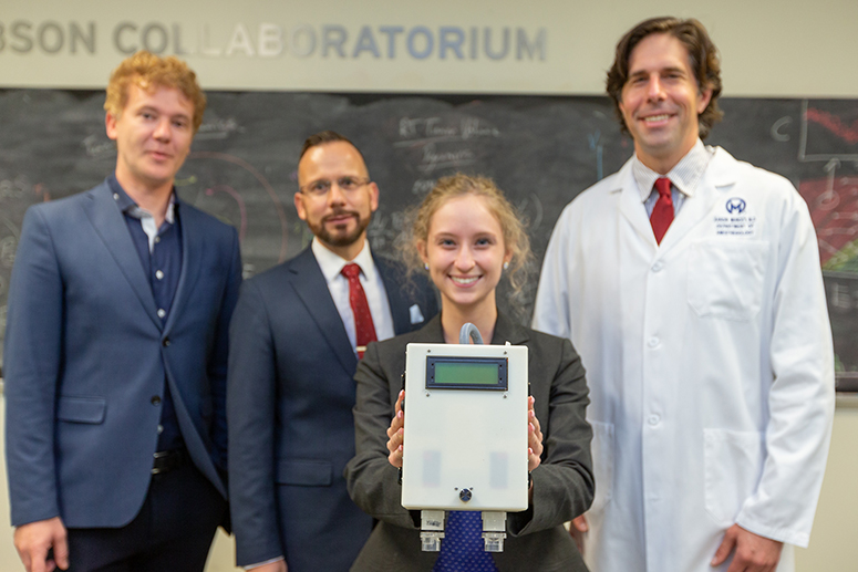 USF student Abby Blocker holds the Eucovent prototype in front of Moffitt researchers Dr. Stefano Pasetto, Dr. Heiko Enderling and Dr. Aaron Muncey.