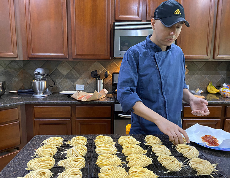 Torres prepares pasta orders in his home kitchen.