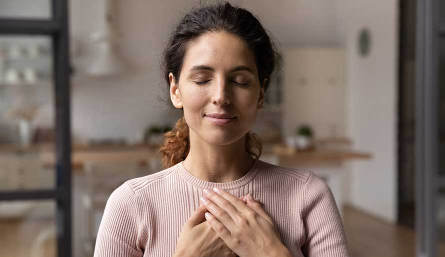 woman with hands clasped on chest