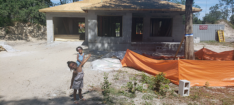 Granger's twin daughters stand in front of the construction site of their new home