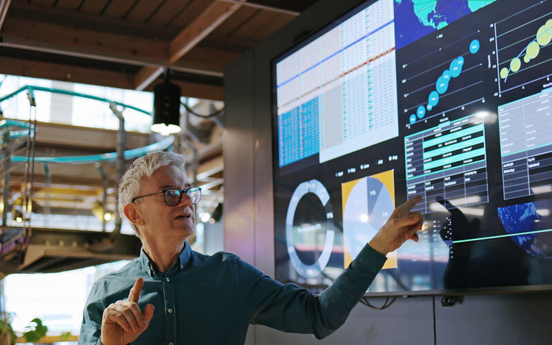 a researcher pointing at a large screen with data on it