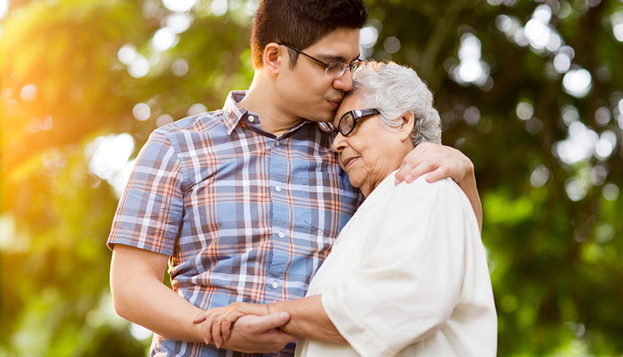 A young man hugs and kisses his grandmother