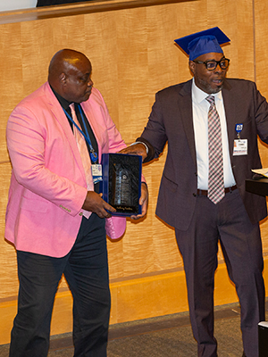 Tony Sanders (left) is presented with a plaque honoring his leadership by graduate Carlos Brown (right).
