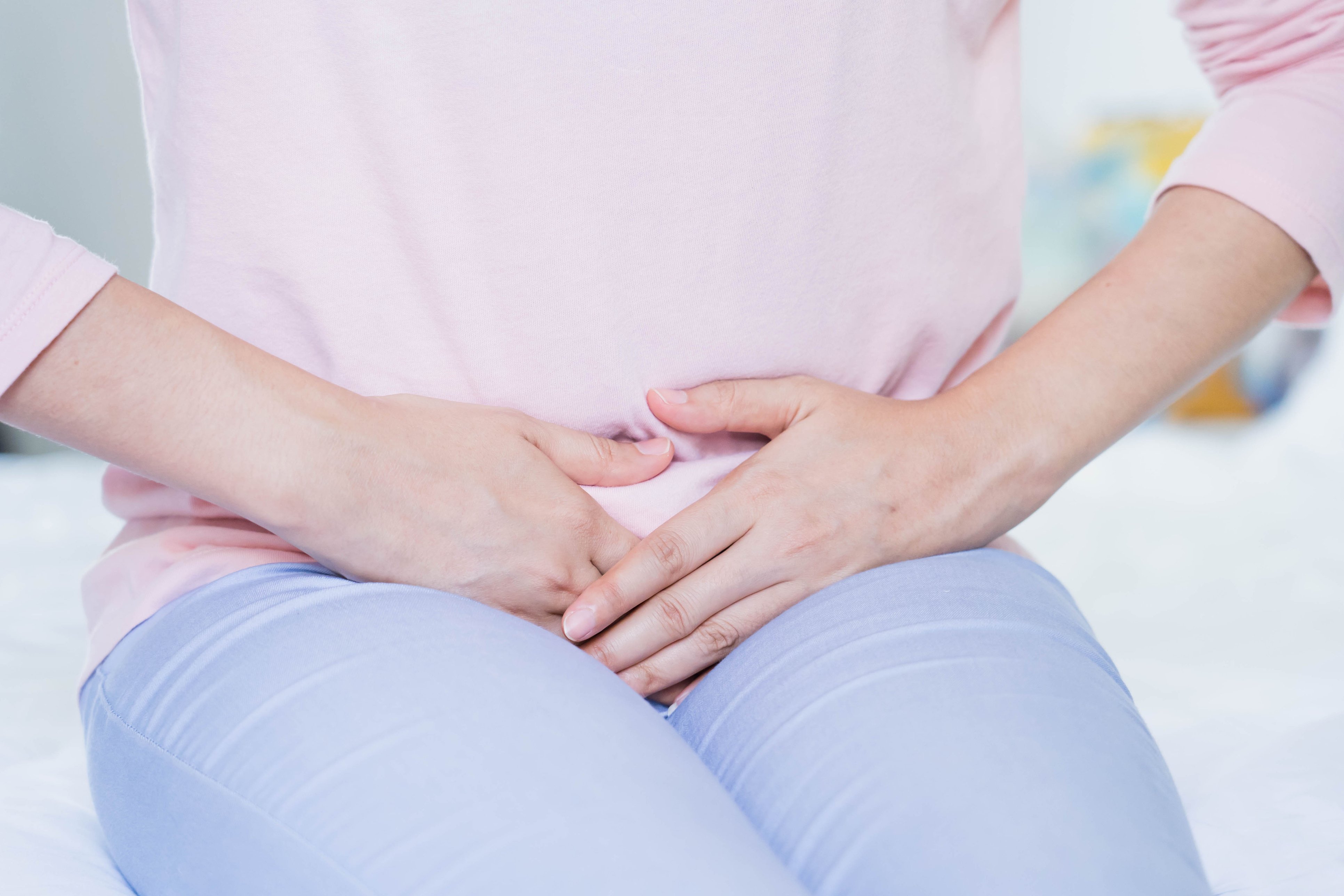woman with possible Bladder Cancer holding hands over abdomen