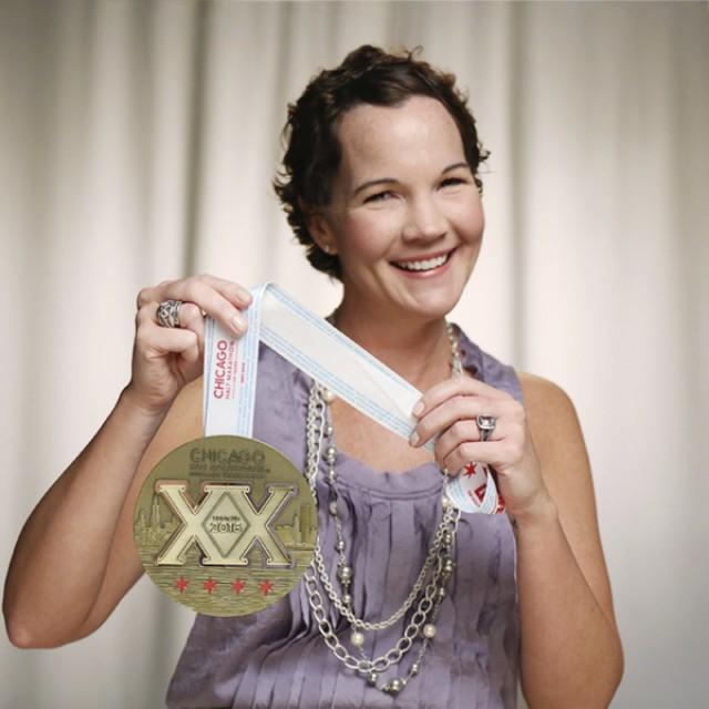 Cathy, a breast cancer survivor, smiling and holding a Chicago Marathon medal. 