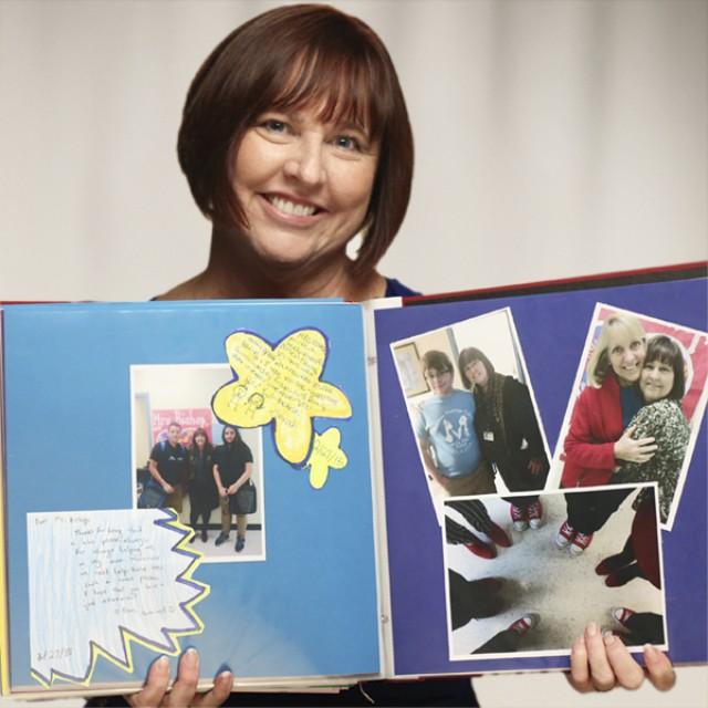 Cathy, colon cancer survivor, holding up pictures of her family in a scrap book. 