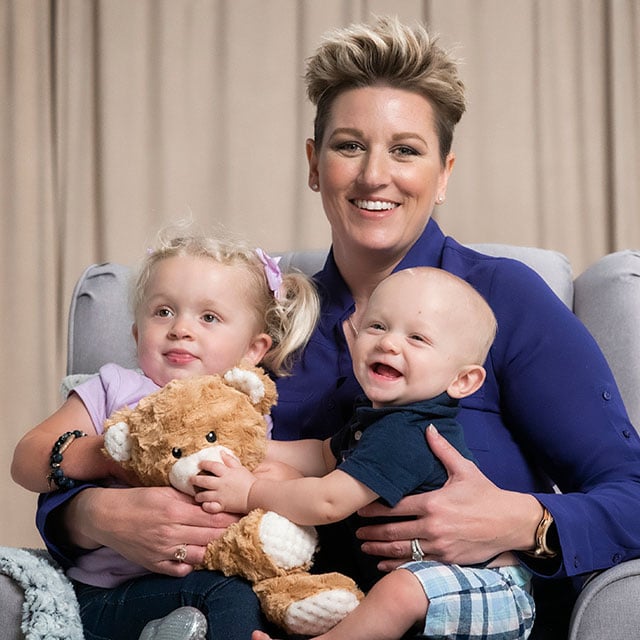 Jessica is a metastatic breast cancer survivor posing with her toddler girl and baby boy.