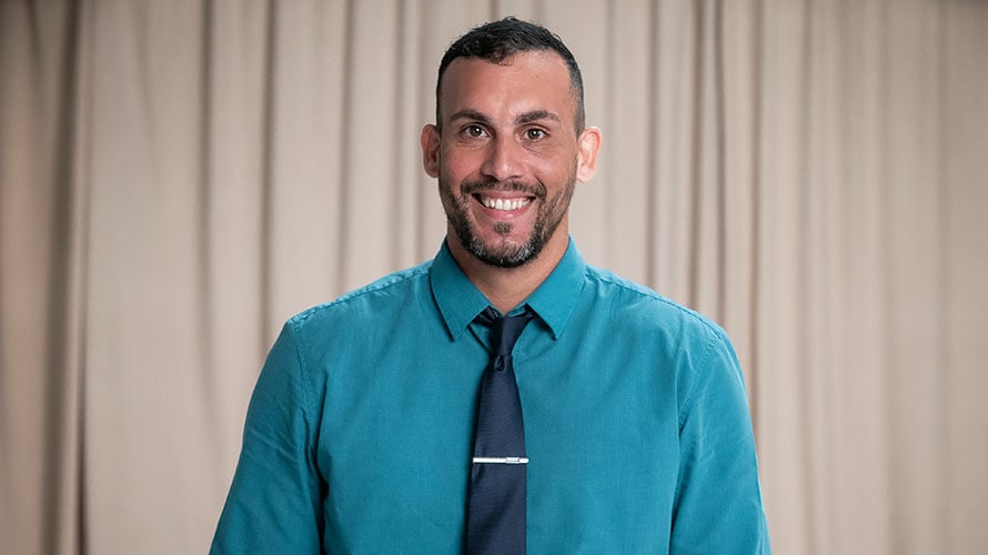 Joel, Hodgkin Lymphoma survivor, smiles for the camera wearing a dress shirt and tie.