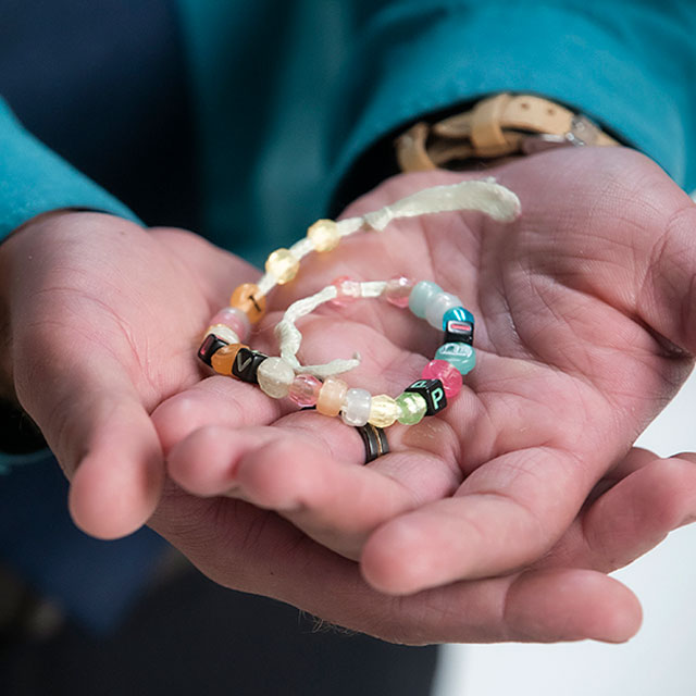Close shot of Joel's hands holding a bracelet his daughter made him.