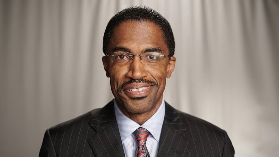 Lanse, prostate cancer survivor, smiling in a suit and tie. 