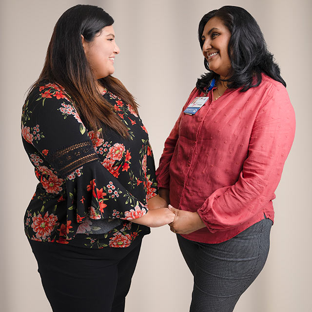 Viviana, breast cancer survivor, holding hands with a woman supporter at Moffitt. 