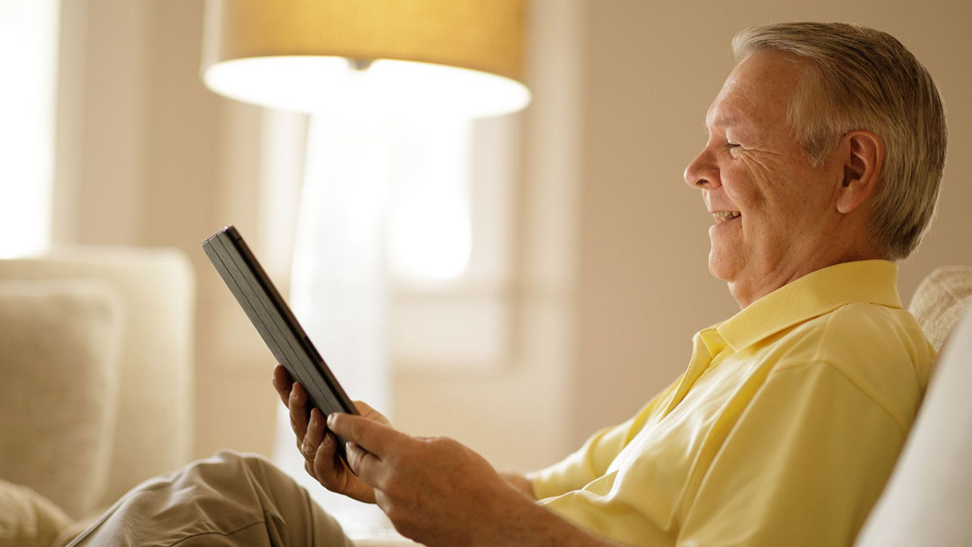 Man sitting in chair looking at tablet.