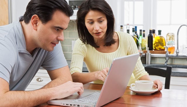 A couple looking a computer for insurance options.