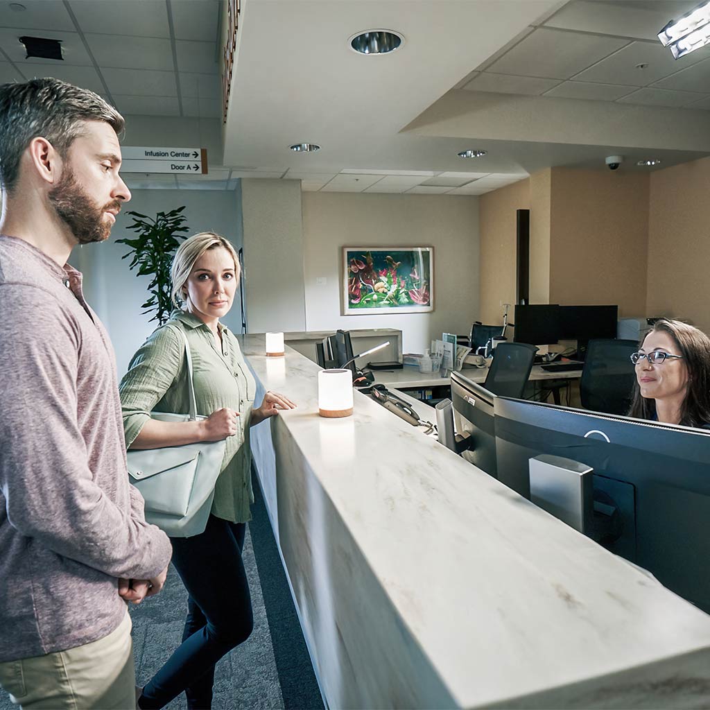 A patient and partner being greeted by a Moffitt receptionist 